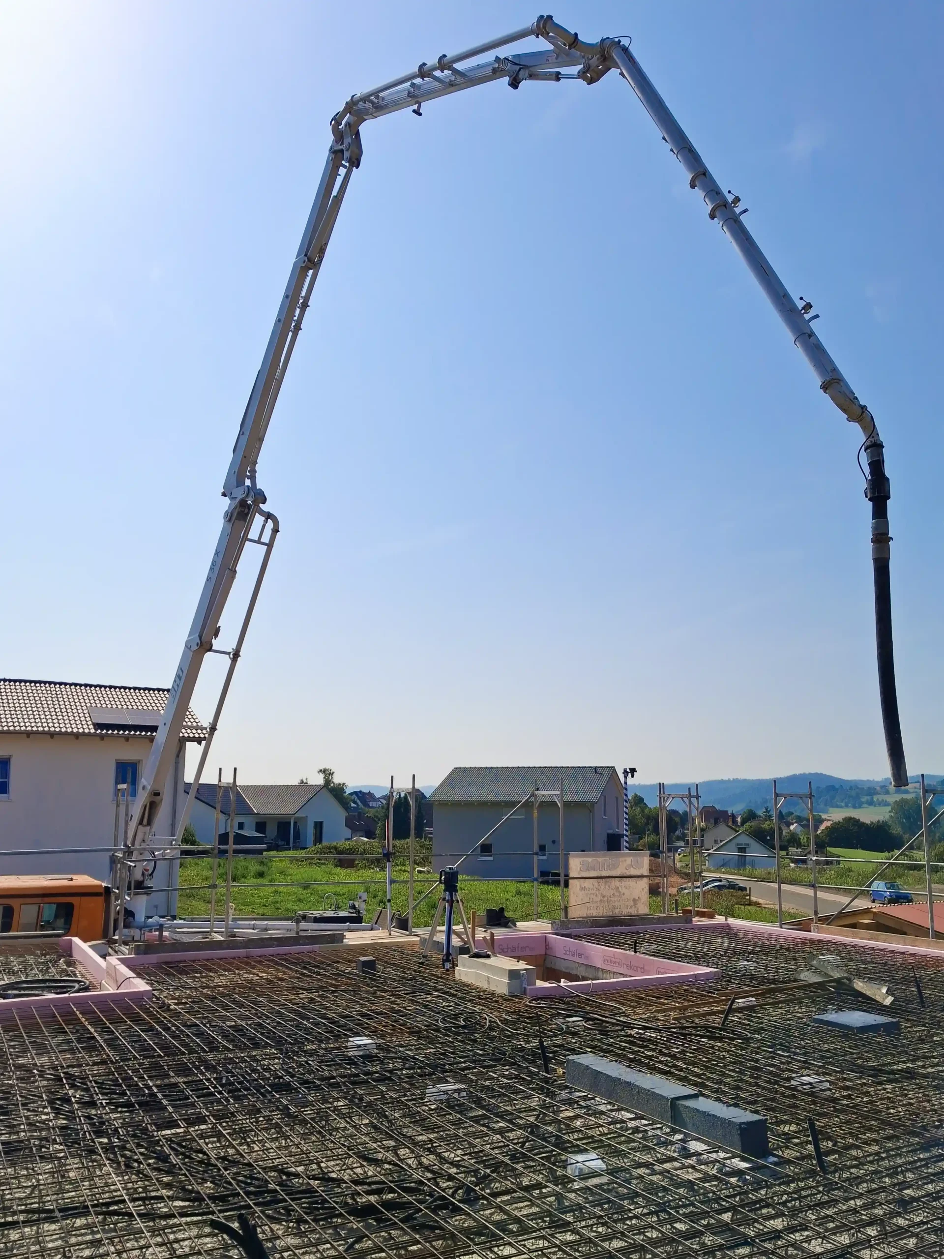 Einsatz einer fahrbaren Betonpumpe mit langem Ausleger über einer vorbereiteten Bewehrung für eine Bodenplatte in Allheim-Heinebach – durch André Franz Bau.