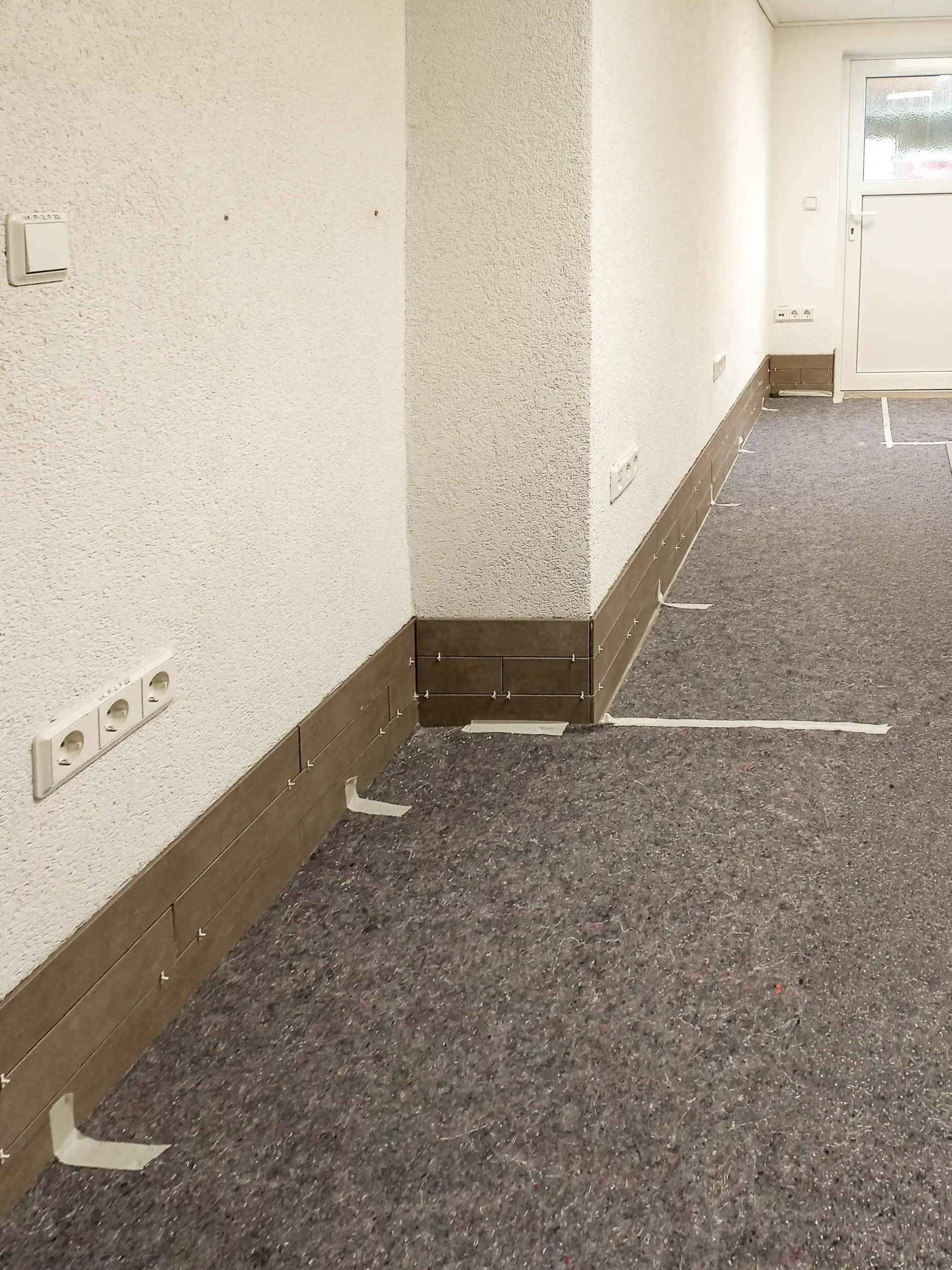 Kleben von Wandriemchen als Sockelleiste in einem Innenraum in Nentershausen/ Andre Franz Bau