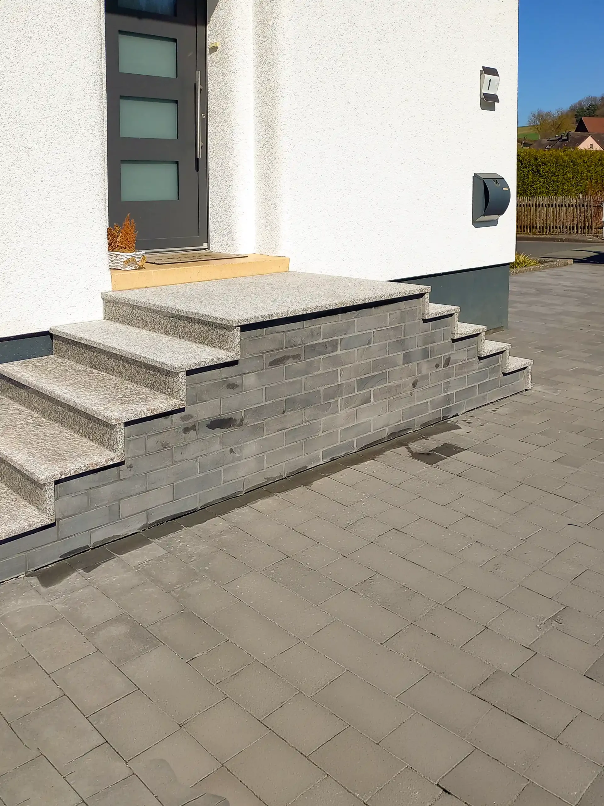 Treppenverkleidung im Eingangsbereich mit Granitstufen und dunklen Riemchen in Bebra-Gilfershausen - durch André Franz Bau